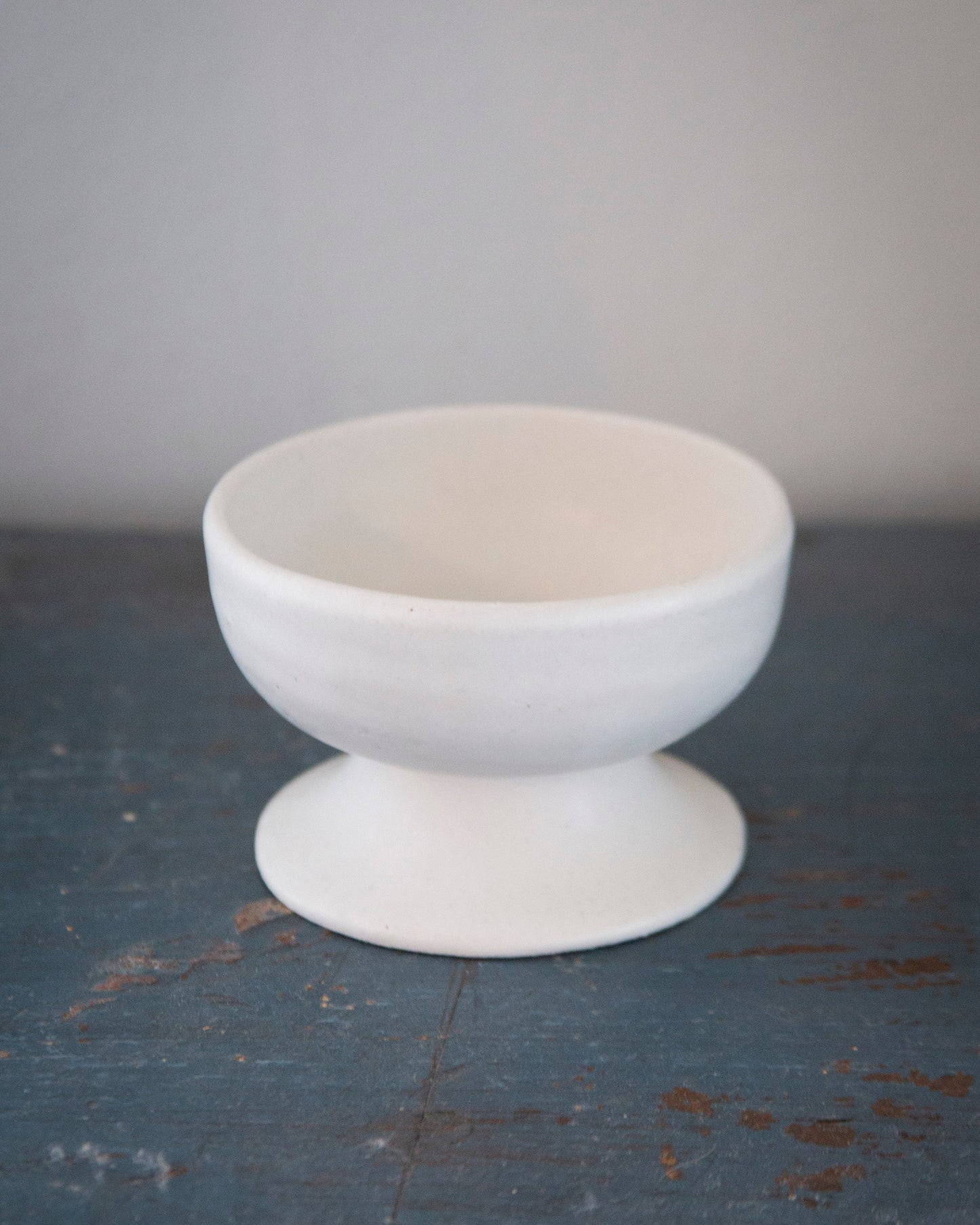 White ceramic bowl on a textured dark surface with a light gray background
