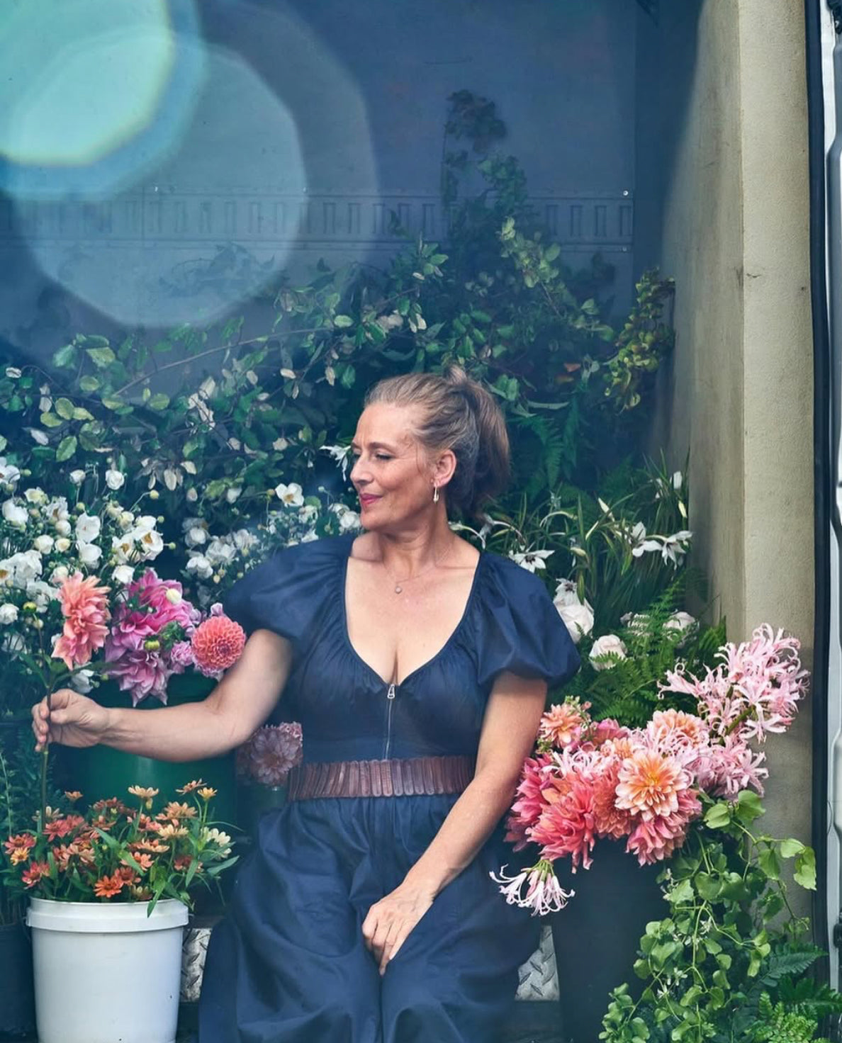 Ariella Chezar and Anne Long Floral Retreat at The Dahlia House in Skagit Valley WA. Woman in a blue dress standing among flowers with a blurred background