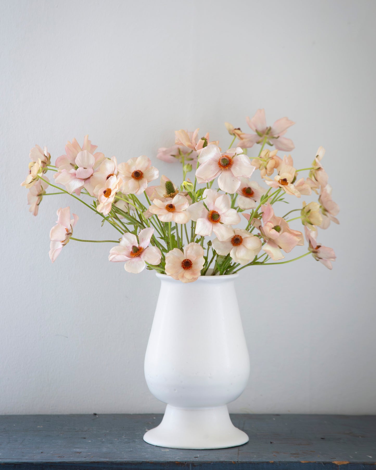 White vase with flowers on a gray surface against a light gray background