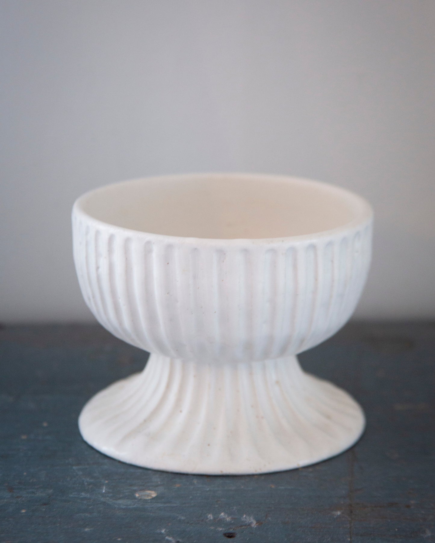 White textured ceramic bowl on a dark surface with a light gray background