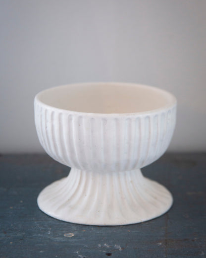 White textured ceramic bowl on a dark surface with a light gray background