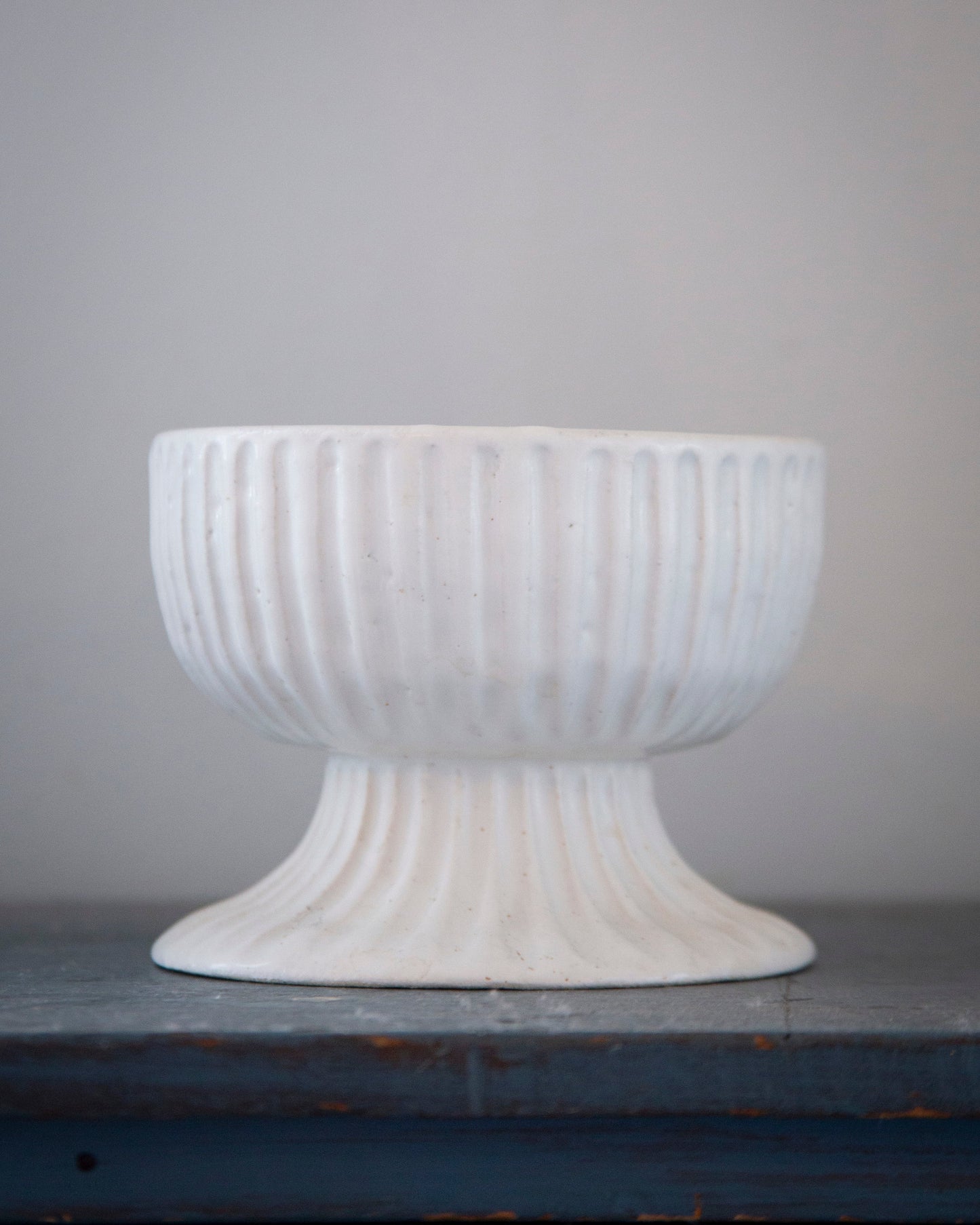 White textured pedestal bowl on a gray surface with a gray background