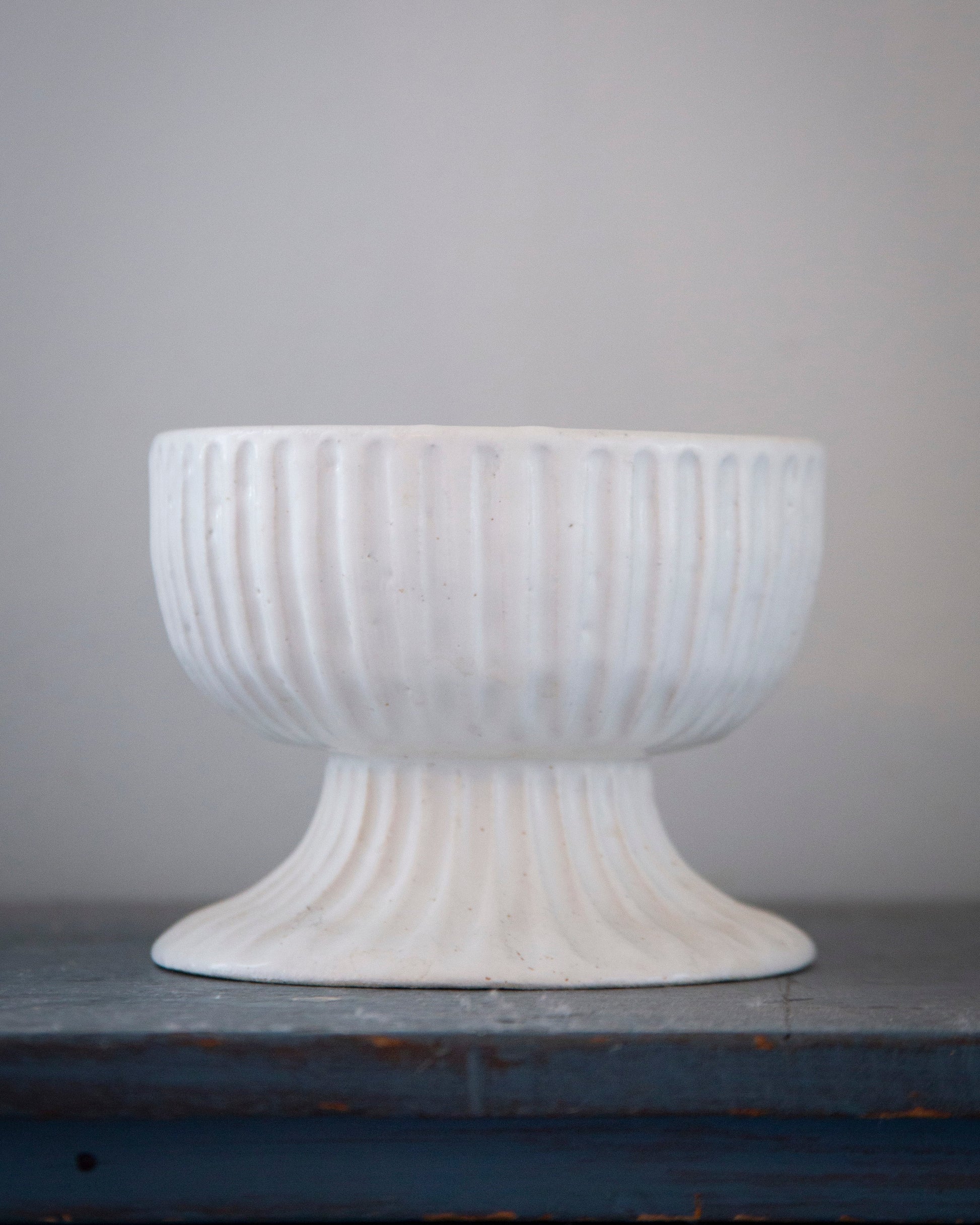 White textured pedestal bowl on a gray surface with a gray background