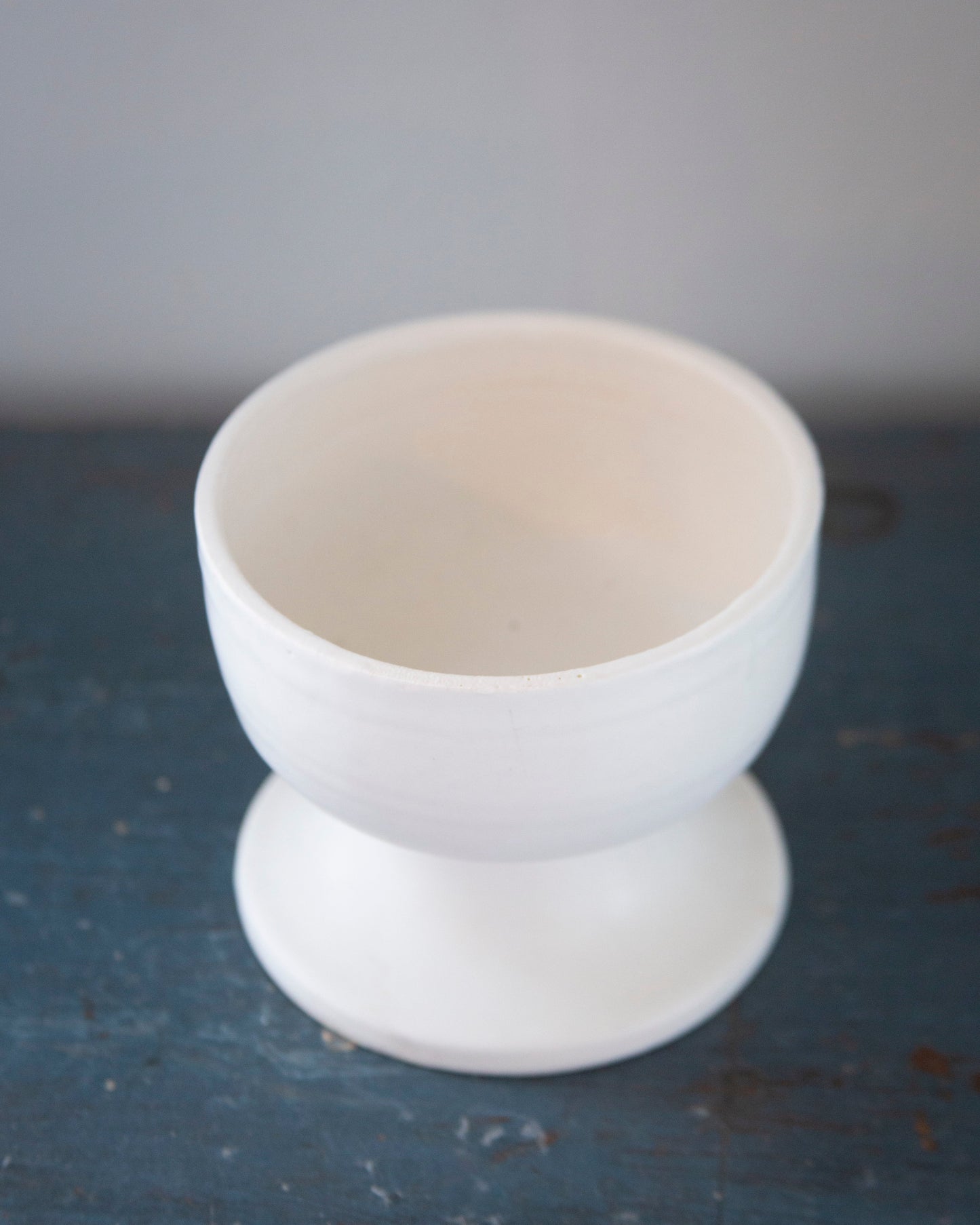 White ceramic egg cup on a dark surface with a gray background