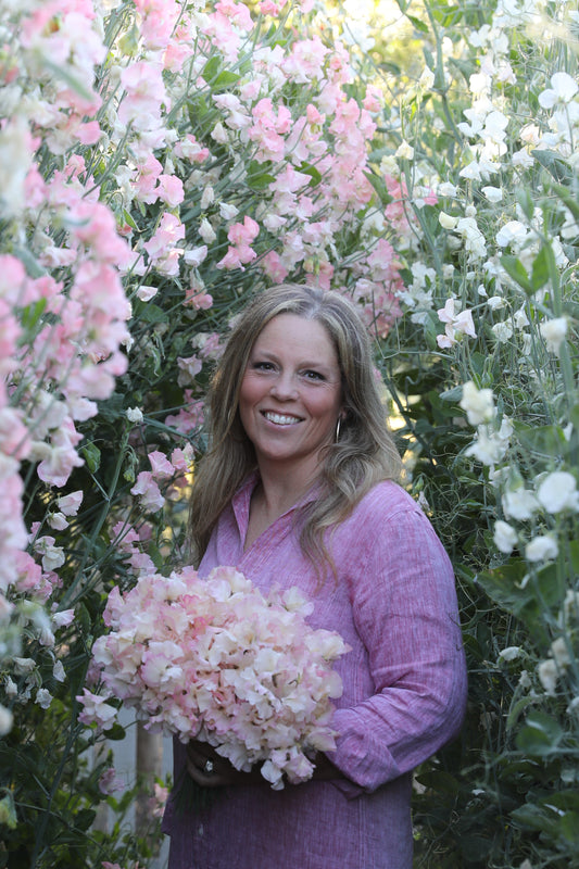 Woman in a field of pink flowers wearing a purple sweater