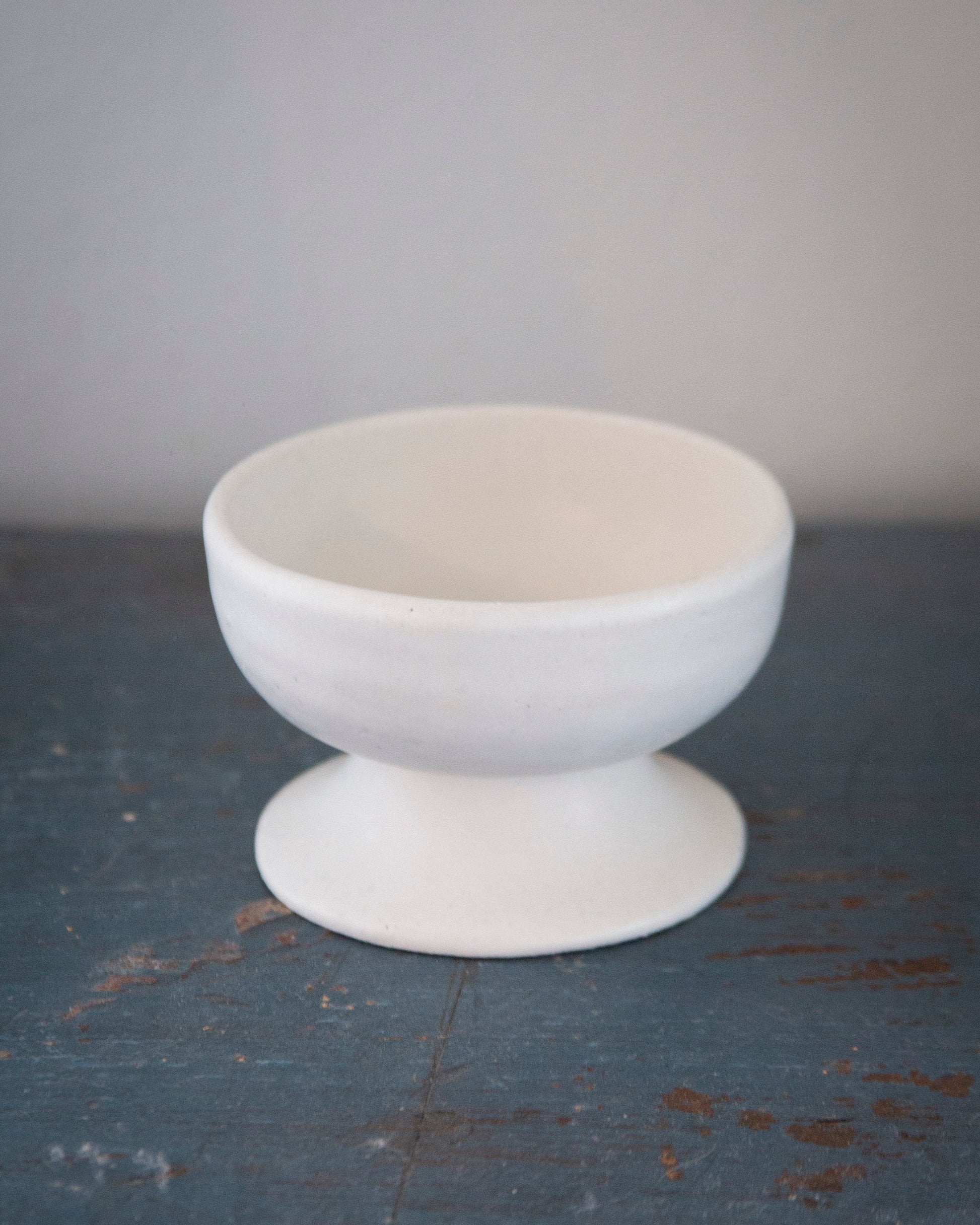 White ceramic bowl on a textured dark surface with a light gray background