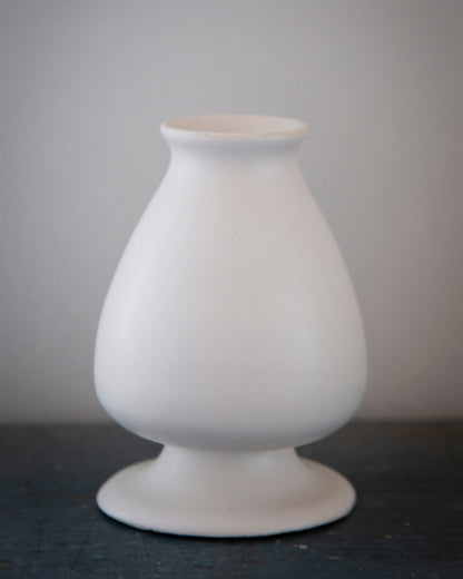 White ceramic vase on a dark surface with a gray background