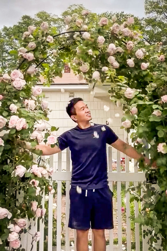 Man standing under a floral archway with a white building in the background