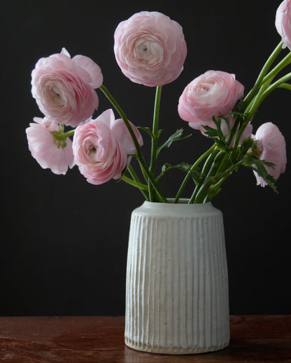White vase with pink flowers on a dark background