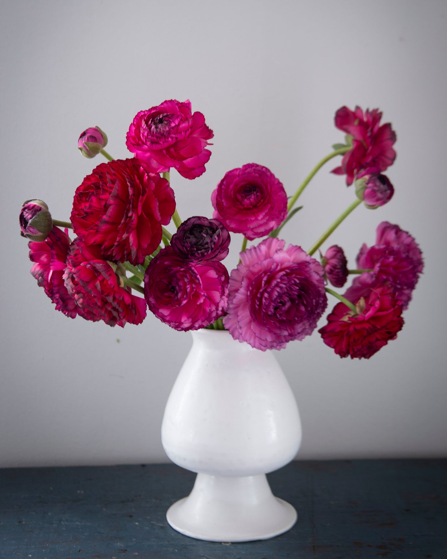 White vase with pink and purple flowers on a gray background